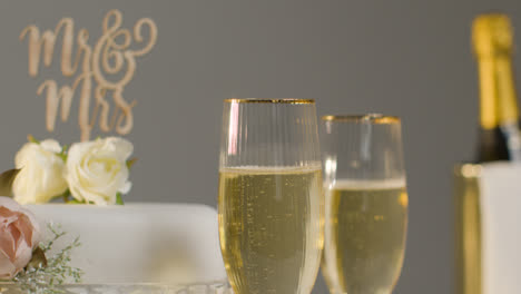 Wedding-Cake-With-Glasses-Of-Champagne-Against-Grey-Studio-Background-At-Wedding-Reception-4